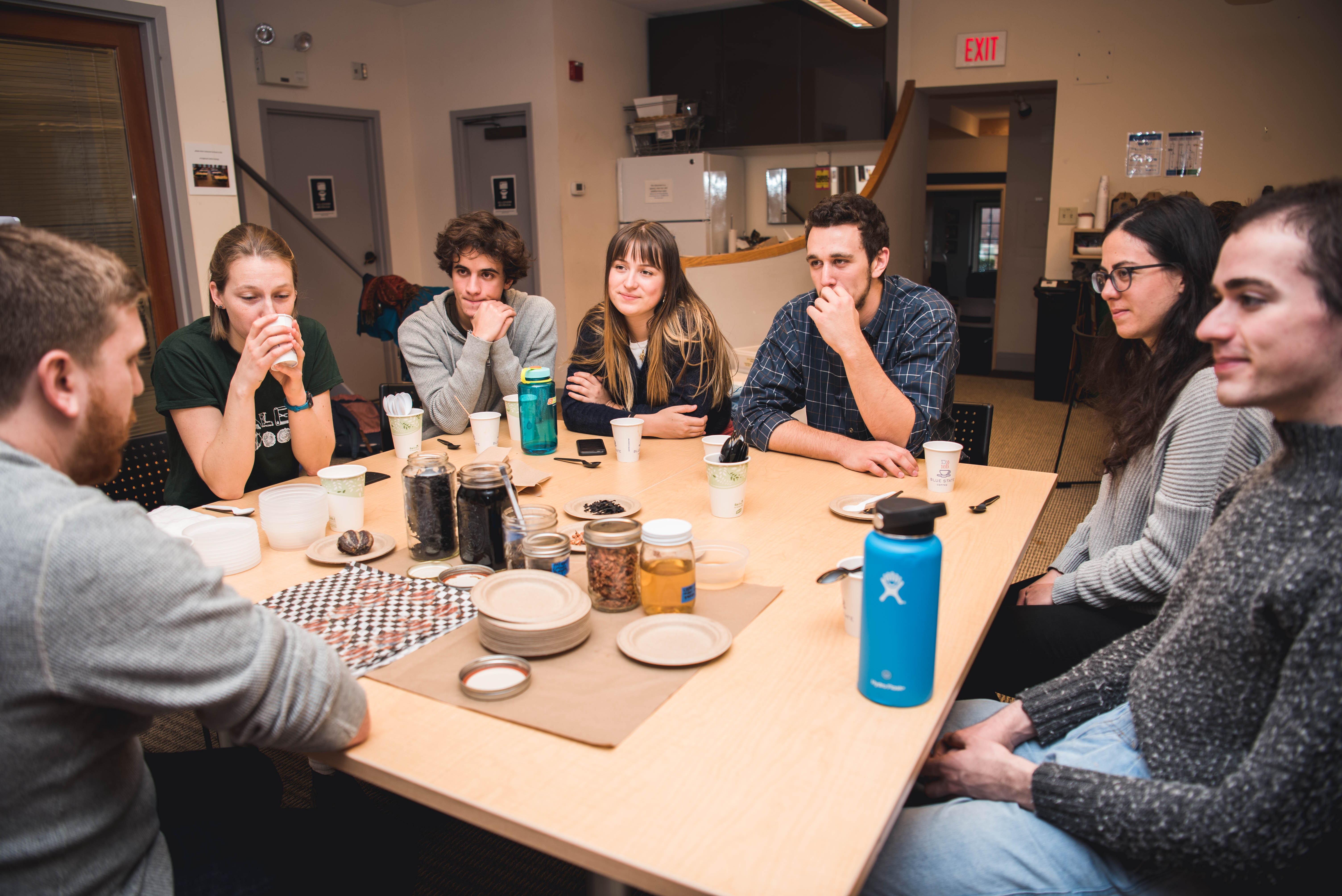 Group of students gather around table with food products